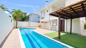 Ein Wohnhaus mit Schwimmbad, überdachter Terrasse und einem zweistöckigen Gebäude.