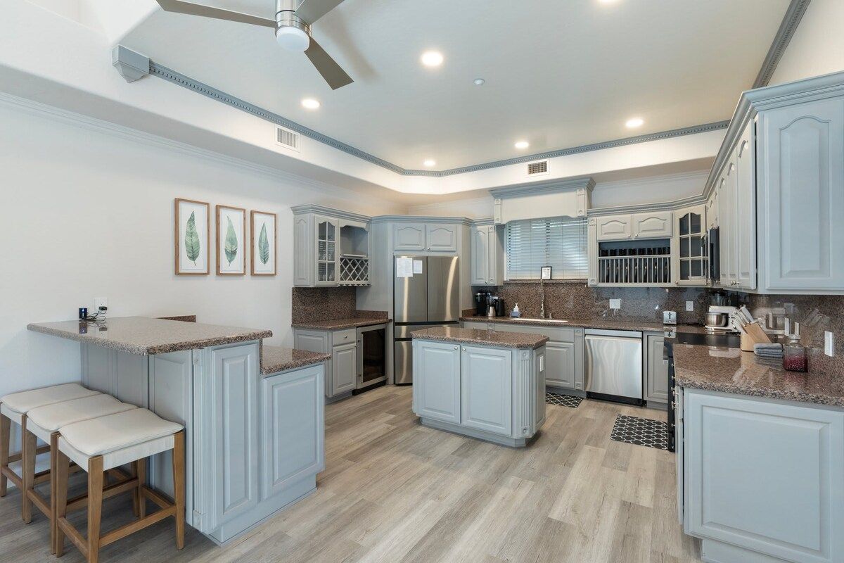 A modern kitchen with granite countertops, stainless steel appliances, and light gray cabinetry.