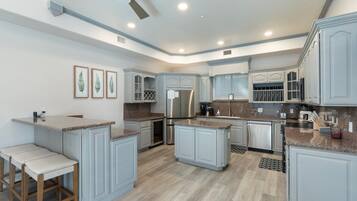 A modern kitchen with granite countertops, stainless steel appliances, and light gray cabinetry.