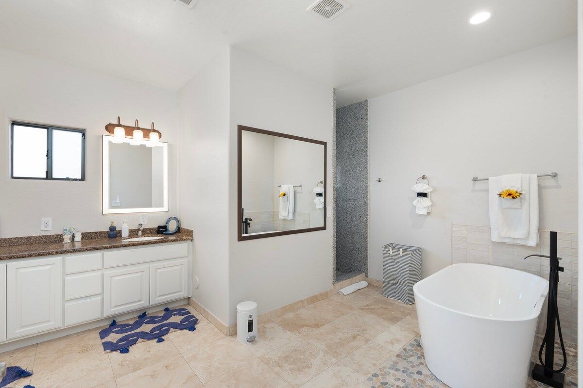 A modern bathroom with a large mirror, a bathtub, and a shower area.