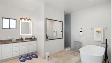A modern bathroom with a large mirror, a bathtub, and a shower area.