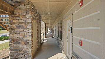 A covered corridor with stone walls, doors, and a fire alarm.