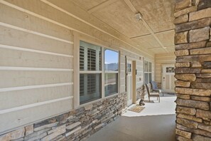 A covered porch with stone walls, large windows, and a stone pillar. - Cades Cove Paradise | Views, Fireplace & MORE! (Townsend)