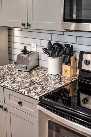 A kitchen with a granite countertop, a toaster, a knife block, and a stove.