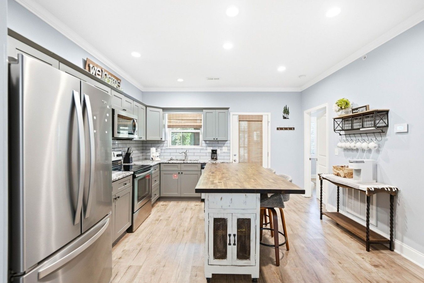 A modern kitchen with stainless steel appliances, a wooden island, and a coffee station.