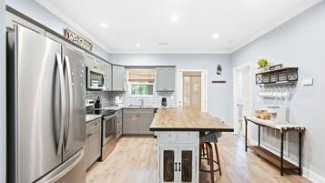 A modern kitchen with stainless steel appliances, a wooden island, and a coffee station.
