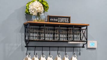 A kitchen area with a coffee station, including a coffee maker, cups, and a basket.