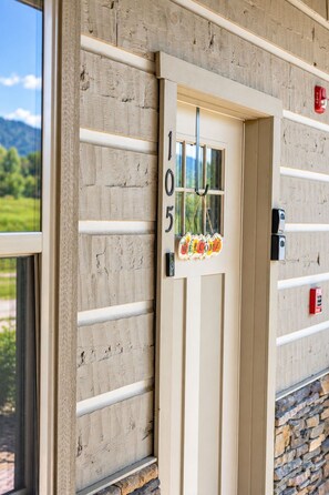 A door with the number 105, a welcome sign, and a view of a stone wall.