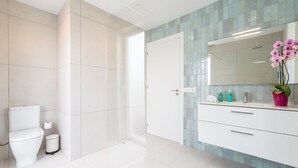 Un baño moderno con inodoro, bidé, ducha y tocador con espejo.