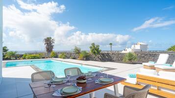 A dining table set for four with a view of the sea and a clear sky.