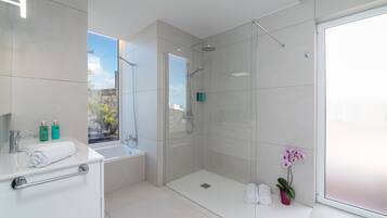 Un baño moderno con cabina de ducha de vidrio, una bañera y un lavabo con una toalla.
