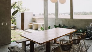 Um interior moderno com teto de concreto, mesa de madeira e luminárias pendentes esféricas.
