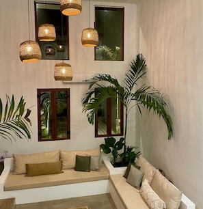 A modern living room with a sofa, large windows, and hanging wicker lamps.
