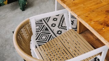 A wooden dining table with woven chairs and a patterned rug.