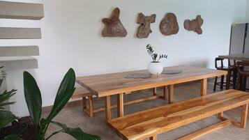 A wooden dining table with benches, a potted plant, and wall-mounted decorative pieces.