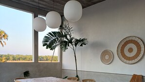 Uma área de refeições com uma mesa de madeira, bancos e cadeiras, rodeada por um tapete estampado.
