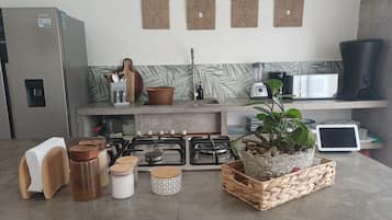 A kitchen with a refrigerator, stove, microwave, and various kitchen utensils.