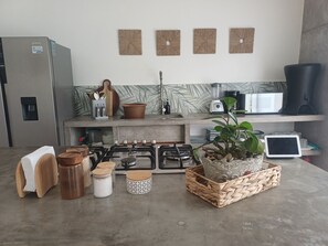 Una cocina equipada con refrigerador, estufa, microondas y varios utensilios de cocina.