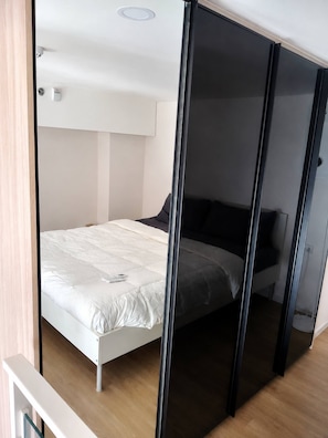 A modern bedroom with a bed, a white ceiling, and a wall-mounted light fixture. - Room-city View Modern Condo in Bangkok C (Bangkok)