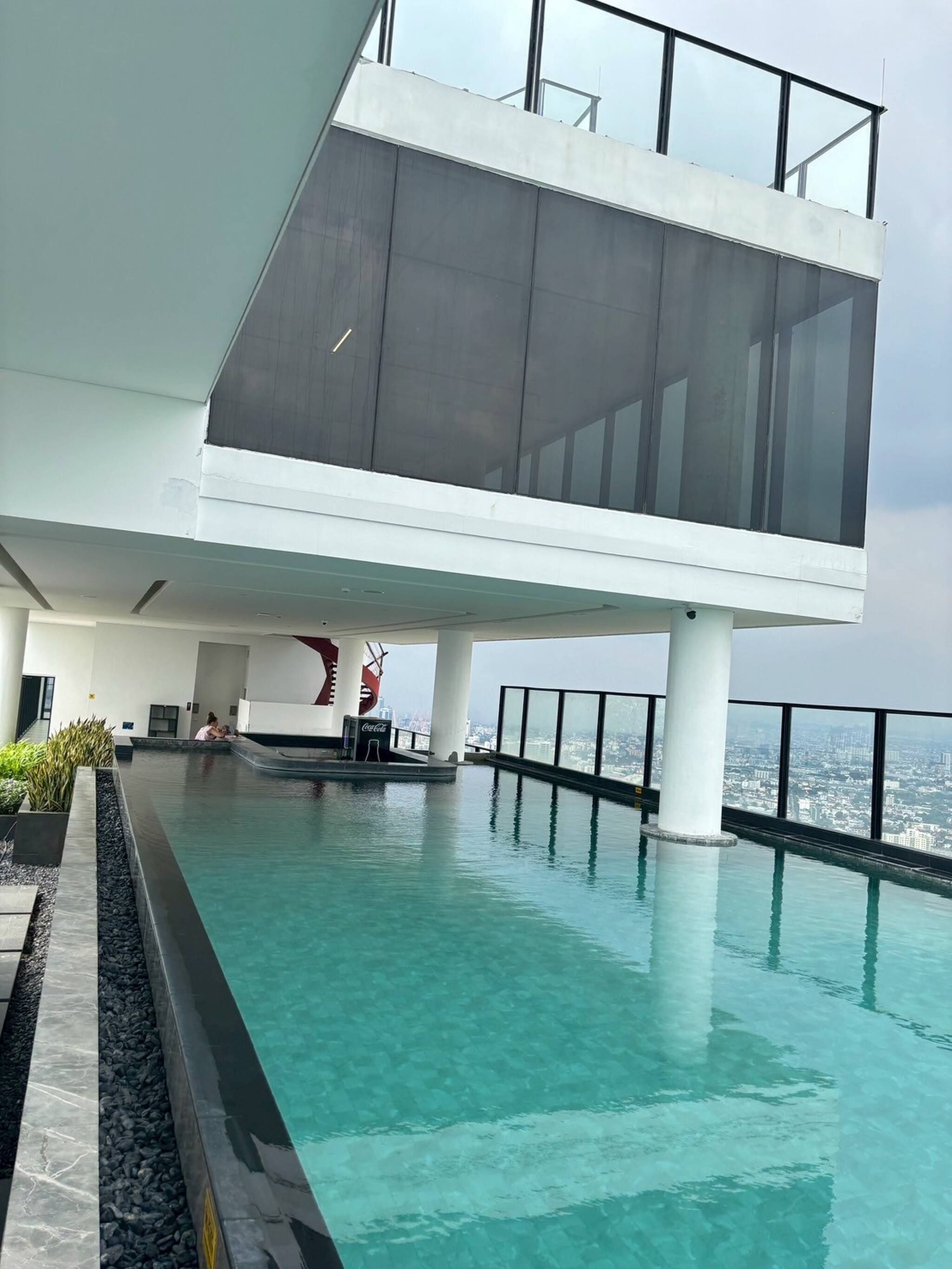 A modern building with a rooftop pool, large windows, and a view of the city.