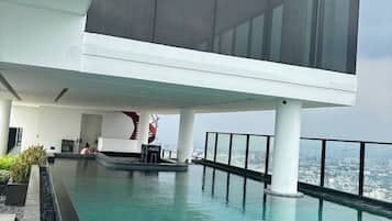 A modern building with a rooftop pool, large windows, and a view of the city.