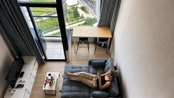 Uma sala de estar moderna com uma janela ampla, um sofá, uma mesa de centro e um espaço para refeições.