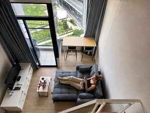 Uma sala de estar moderna com uma janela ampla, um sofá, uma mesa de centro e um espaço para refeições.