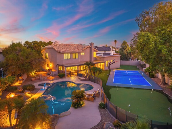 A large house with a swimming pool, tennis court, and outdoor seating area. - Luxury 5BR Retreat, Heated Pool, Spa, Sport Court, Putting Green & Game Rooms (Scottsdale)