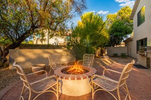 A circular fire pit with chairs around it, a barbecue grill, and a tree in the background. - Luxury 5BR Retreat, Heated Pool, Spa, Sport Court, Putting Green & Game Rooms (Scottsdale)