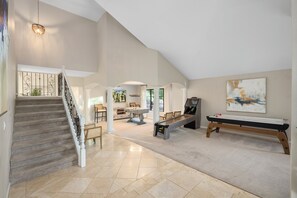 A spacious living area with a staircase, a pool table, and a foosball table. - Luxury 5BR Retreat, Heated Pool, Spa, Sport Court, Putting Green & Game Rooms (Scottsdale)