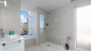 Une salle de bain moderne avec une douche à parois de verre, une baignoire et un lavabo avec un porte-serviette.