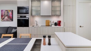 Eine kleine Küche mit Mikrowelle, Backofen und modernen Schränken.