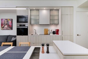 A compact kitchen with a microwave, oven, and modern cabinetry. - Stylish Yorkville 1BR Central & Convenient (Toronto)