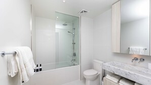 Ein modernes Badezimmer mit einer gläsernen Duschkabine, einer Toilette und einer Marmorwaschtischplatte mit Waschbecken.