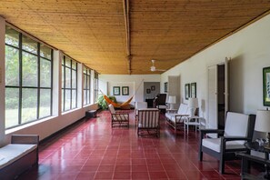 Une pièce spacieuse avec de grandes fenêtres, un plafond en bois et un sol carrelé de tuiles rouges.