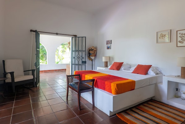 Une chambre d’hôtel avec un lit, une chaise, un bureau, une lampe et une vue sur l’extérieur.