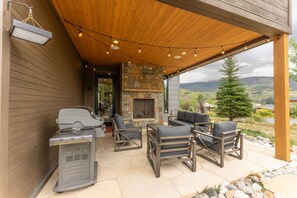 Une terrasse extérieure dotée d’une cheminée en pierre, de sièges et d’un barbecue.