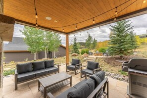 An outdoor patio with a wooden ceiling, stone flooring, and a barbecue grill. - Pet Friendly Mountain Retreat | Private Hot Tub | Private Firepit | Direct Trail Access (Silverthorne)