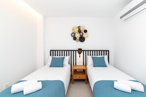 A hotel room with two beds, a wall-mounted lamp, and a decorative wall piece. - Vacation Villa 'Ereza Royal Elite Hoopoe 109' with Sea View, Wi-Fi and Air Conditioning (Playa Blanca)