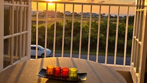Ein Balkon mit Blick auf einen Sonnenuntergang, ein Auto auf der Straße und ein Tablett mit Kerzen.