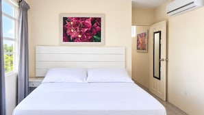 Ein Hotelzimmer mit Bett, Nachttisch, Schrank und einem Fenster mit Vorhängen.