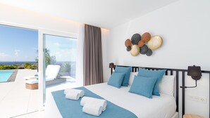 Quarto de hotel com cama, vista para o mar e varanda com espreguiçadeiras.