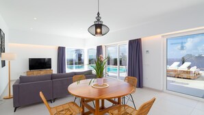 Uma sala de estar moderna com sofá, televisão, mesa de jantar e cadeiras.