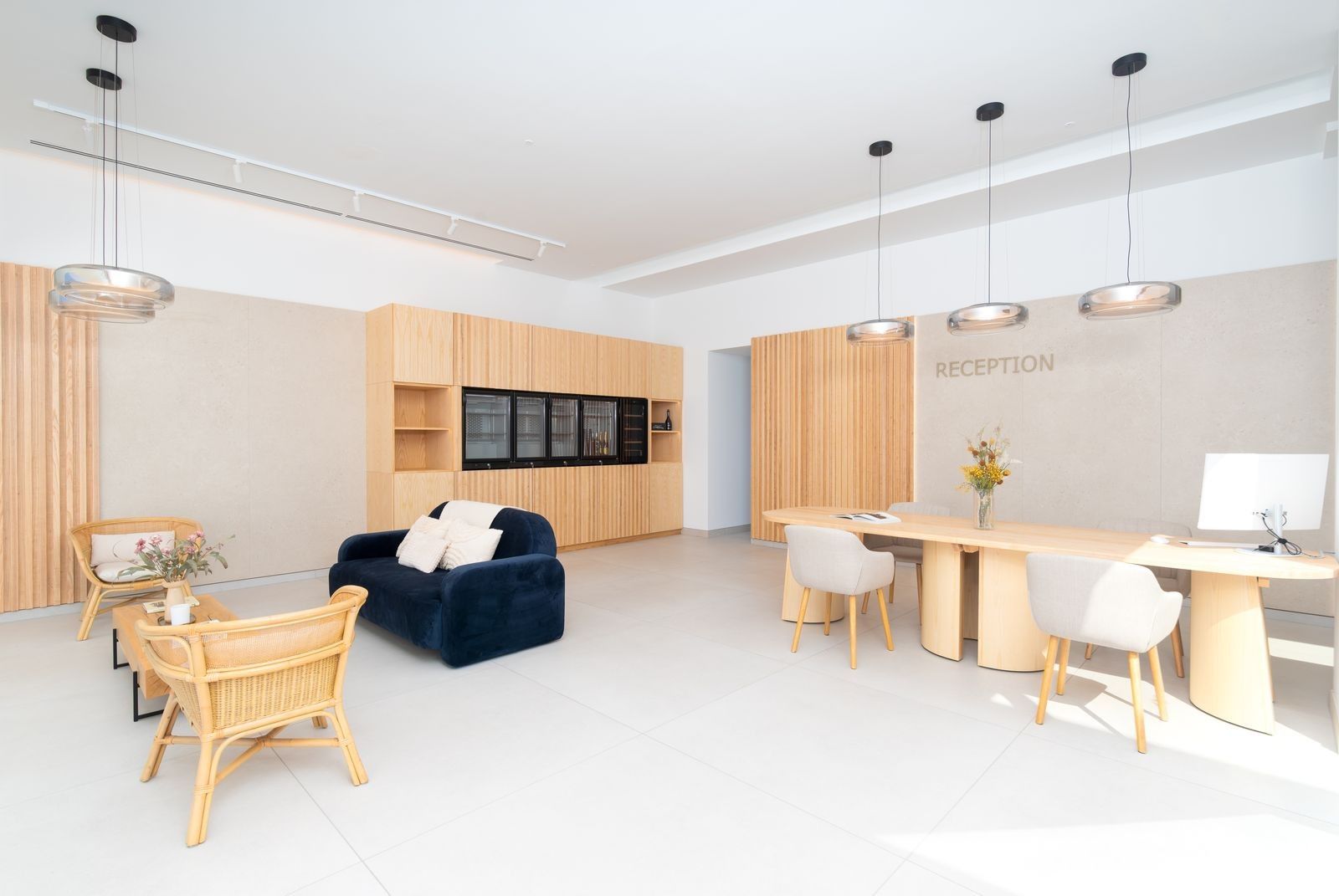 Un área de recepción moderna con mostrador, asientos y una pantalla mural.