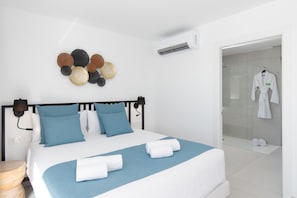 A modern hotel room with a bed, a wall-mounted air conditioner, a decorative wall piece, and a bathroom visible through an open door. - Vacation Villa 'Ereza Royal Elite 111' with Sea View, Wi-Fi and Air Conditioning (Playa Blanca)