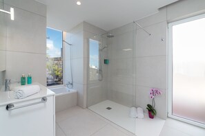 Un baño moderno con cabina de ducha de vidrio, una bañera y un lavabo con una toalla.