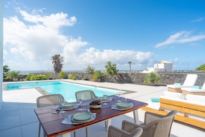 A dining table set for four with a view of the sea and a clear sky. - Vacation Villa 'Ereza Royal Elite 111' with Sea View, Wi-Fi and Air Conditioning (Playa Blanca)