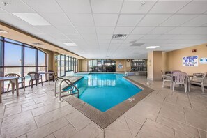 An indoor swimming pool with clear blue water, surrounded by tiled flooring and plastic chairs. - Direct Oceanfront Condo, Top Floor, King, Heated Pools + Hot Tub, Sleeps 9, W... (Orange Beach)