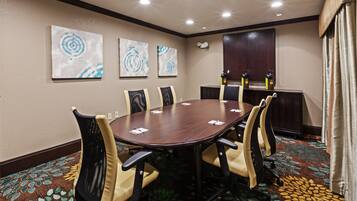 A conference room with a round table, six chairs, and three abstract wall art pieces.