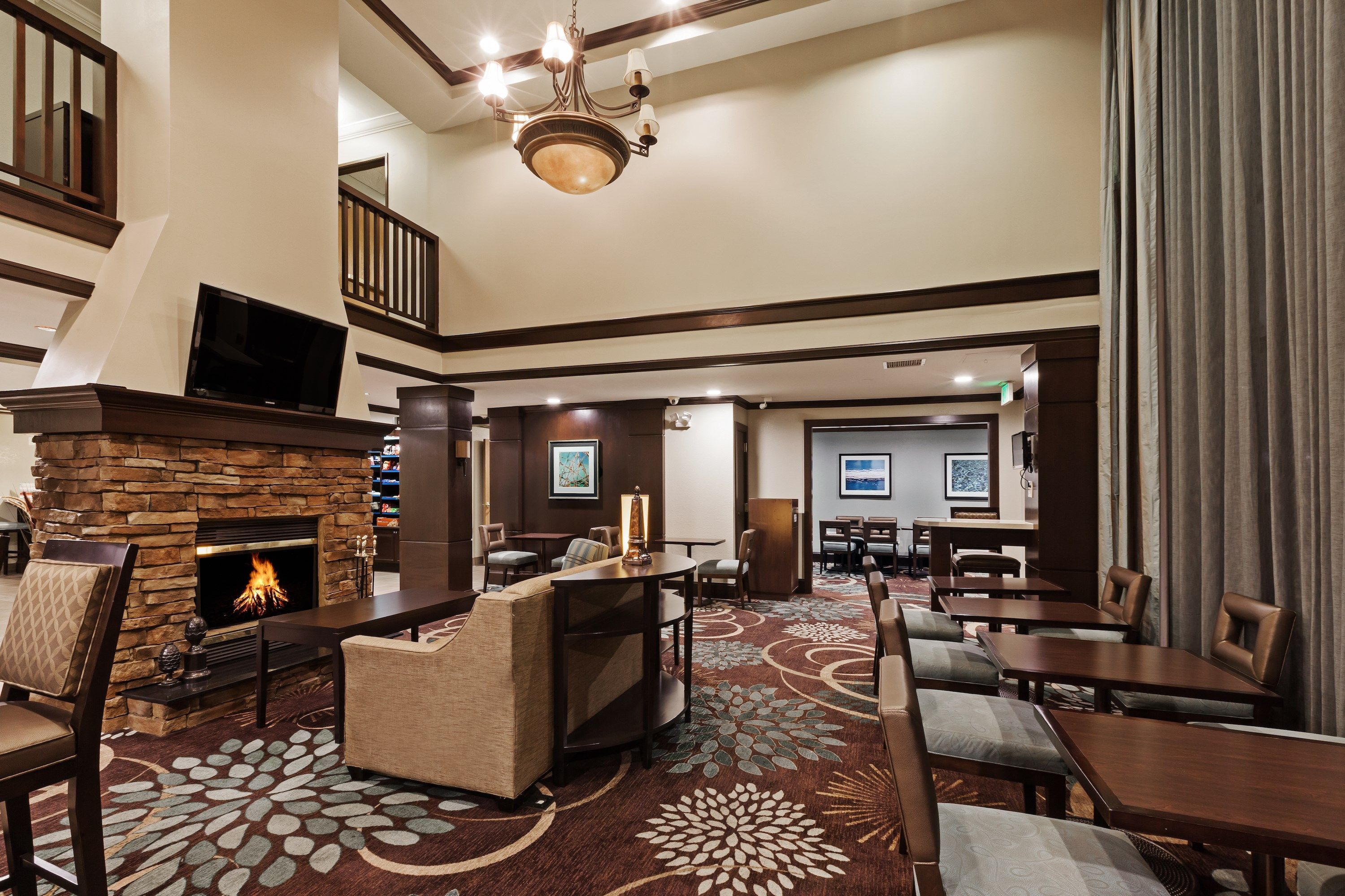 A hotel lobby with a fireplace, seating area, and a staircase.